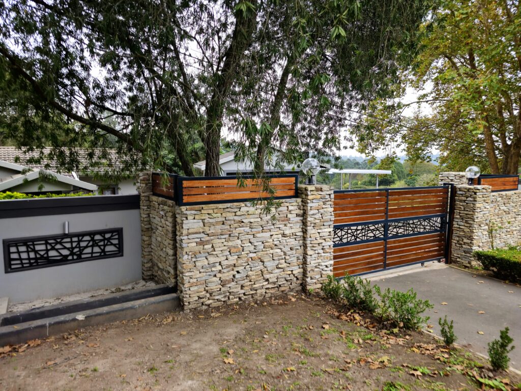 Timber slatted driveway gate between stone walls